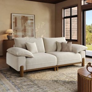 White sofa with oversized pillow-top arms, plush back cushions, and exposed wood frame in a warm modern living room.