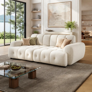 Cream boucle sofa with rounded recessed arms and tufted channel seating in a bright modern living room.