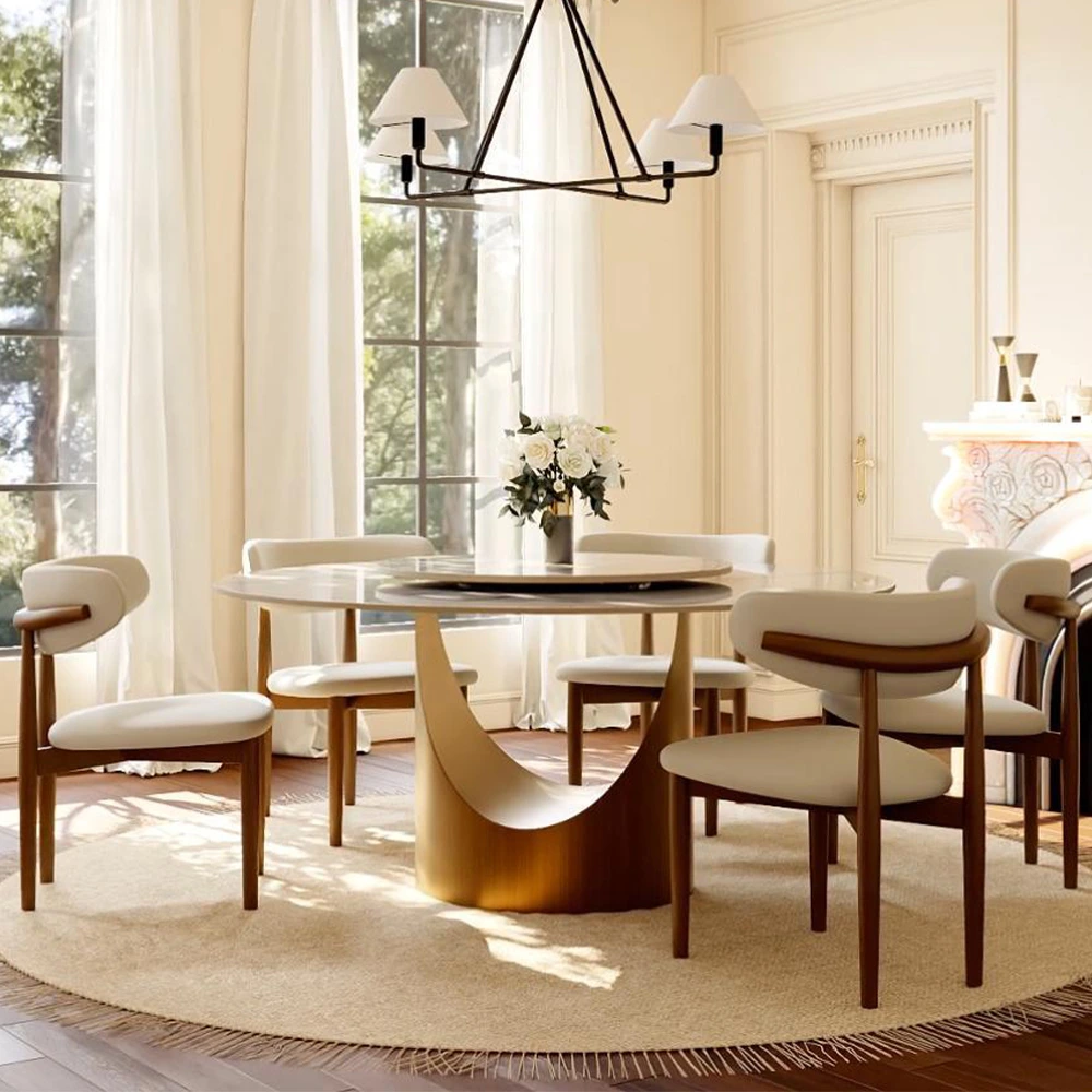 Modern dining room with sintered stone round table and curved back dining chairs in a sunlit space with large windows and neutral tones