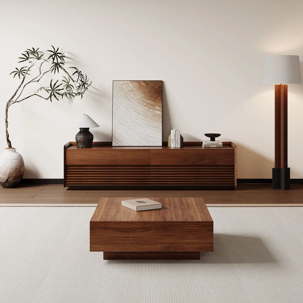 Minimalist modern living room featuring a low square wooden coffee table and a slatted wood sideboard with decorative items, complemented by neutral tones, a tall floor lamp, and a potted sculptural tree.