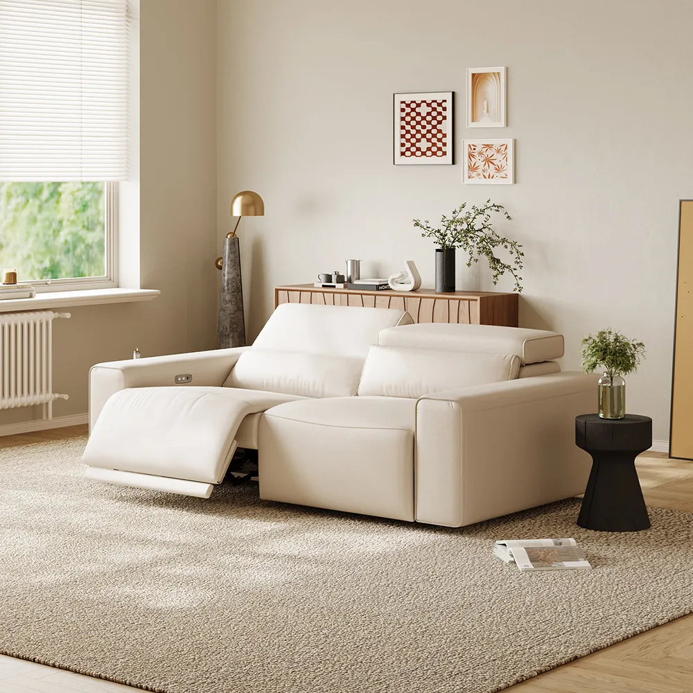 Power recliner sofa with one footrest extended in a soft-toned modern living room with wall art and natural lighting
