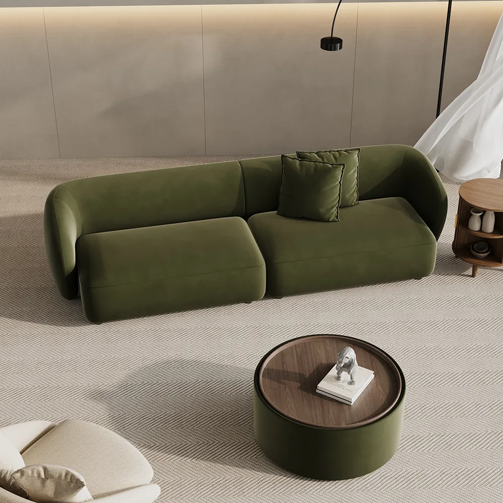 Minimalist olive green curved sofa with round edges, styled with a matching ottoman and warm wood side table on a textured rug