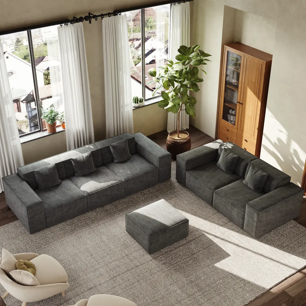 Dark gray modern modular sofa set with matching ottoman, styled in a sunlit living room with tall windows, white curtains, and layered neutral tones