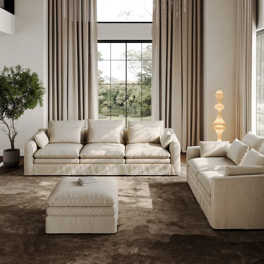 Contemporary beige modular sofa with blocky arms and plush cushions, placed in a cozy sunlit room with neutral decor and modern floor lamp.