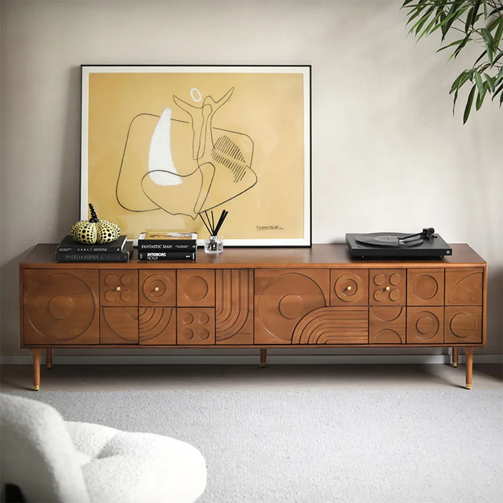Light walnut mid-century modern TV console with circular and linear carvings, styled with minimalist artwork and a record player