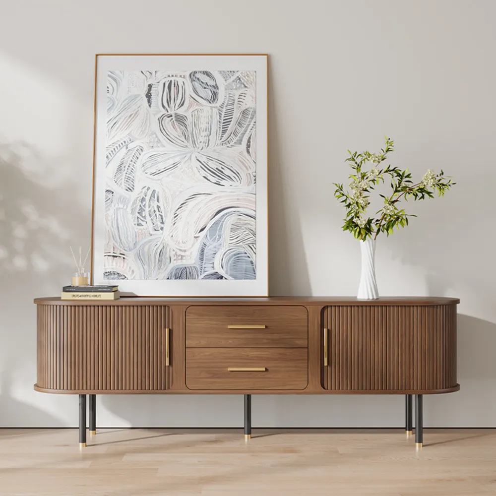 Mid-century modern TV stand with fluted doors and gold hardware, featuring rounded edges and decorative artwork above.