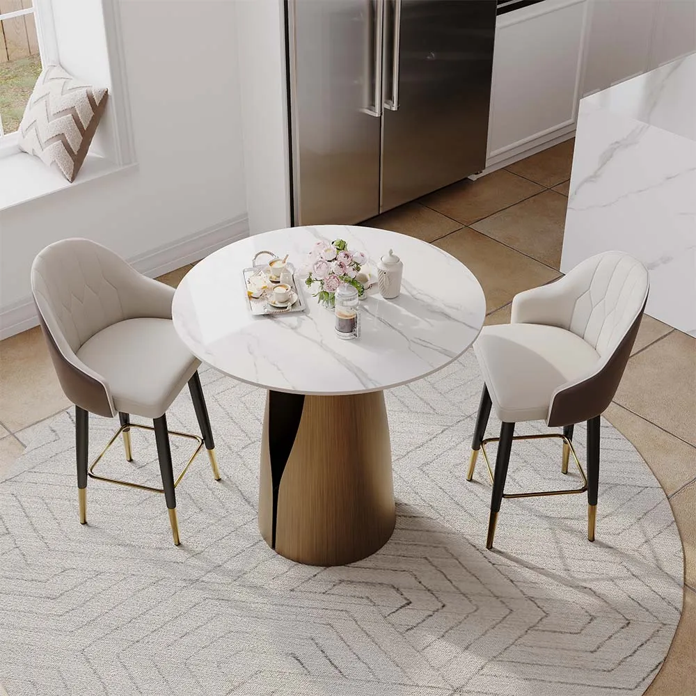 Small round white marble dining table with two upholstered chairs and a gold base, set in a cozy kitchen nook.