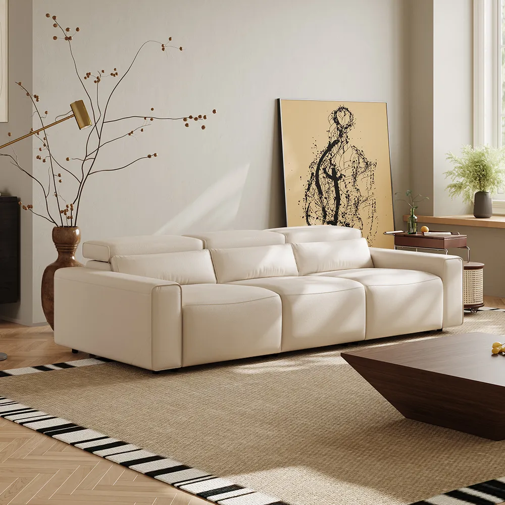 Modern cream leather sofa with adjustable headrests in a minimalist living room featuring neutral tones and soft natural light.