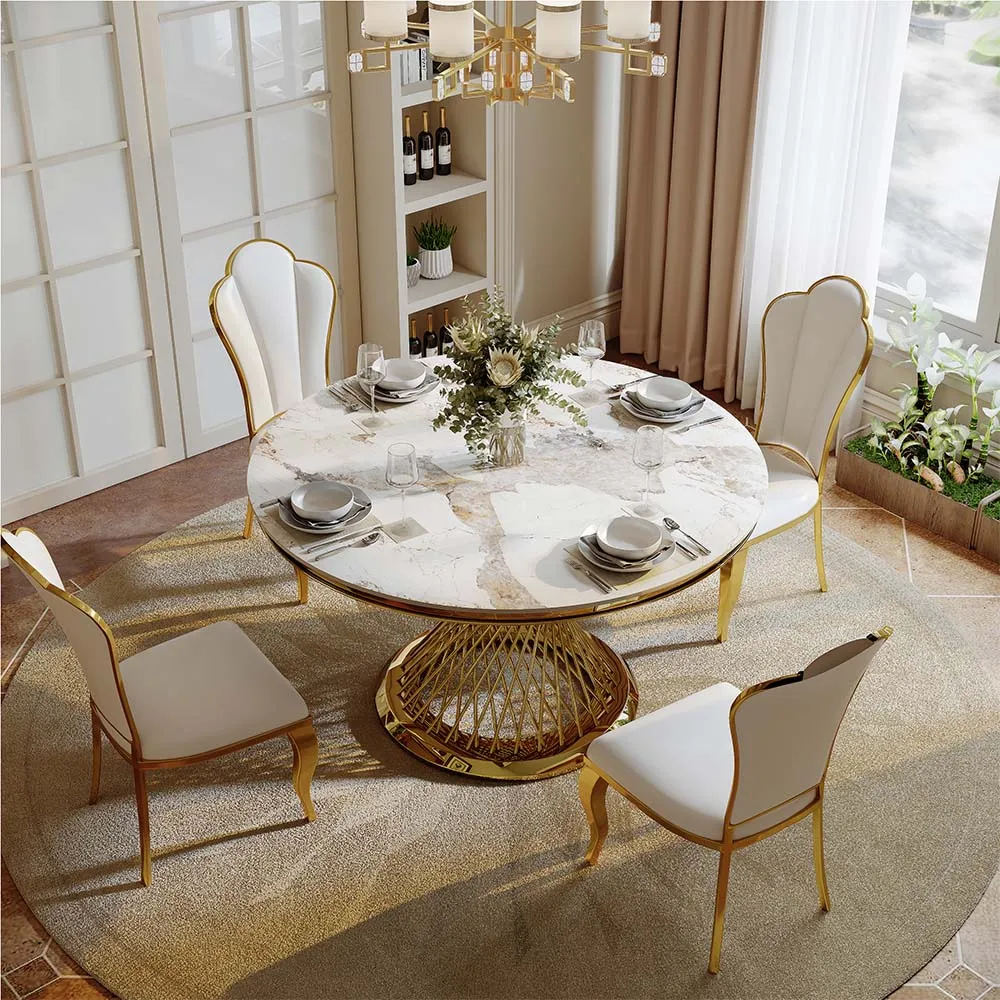 Luxurious round marble dining table with gold wireframe base and white dining chairs in a bright formal dining room.