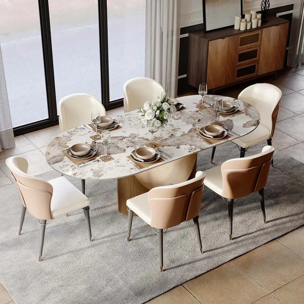 An oval sintered stone dining table with a marble-like surface and beige leather chairs arranged around it, set in a contemporary dining space with soft natural lighting.