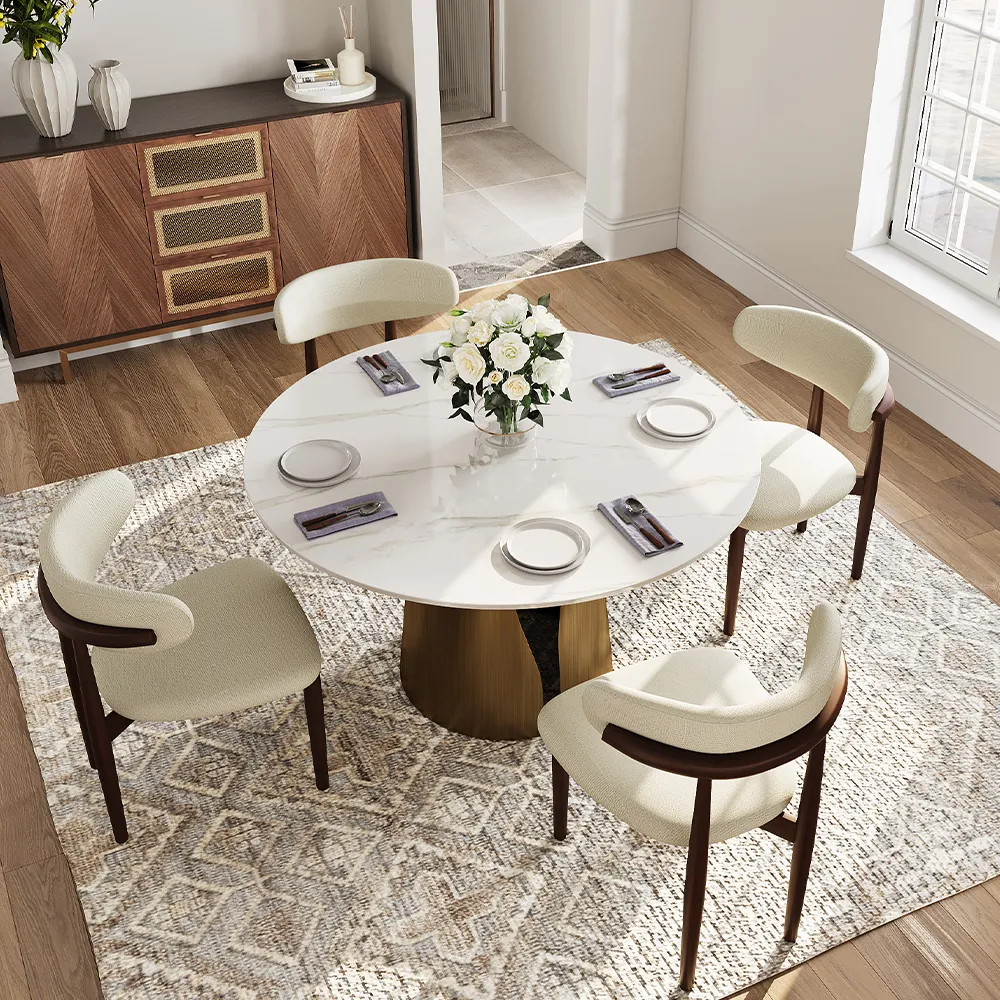 Modern luxury dining room with a black sintered stone rectangular dining table, cream leather chairs, and gold-accented table settings on a patterned gray rug