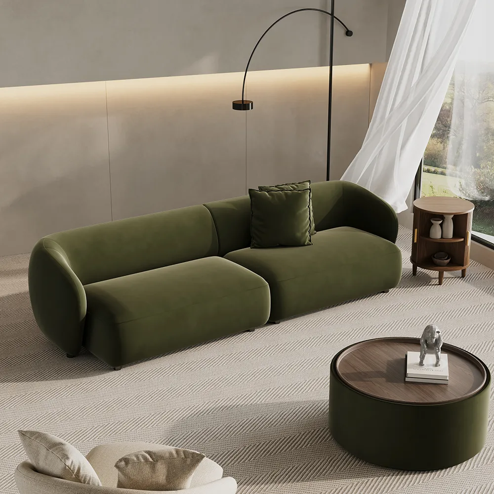 Olive green curved modular sofa in a modern living room with neutral walls, large windows, and sculptural floor lamp