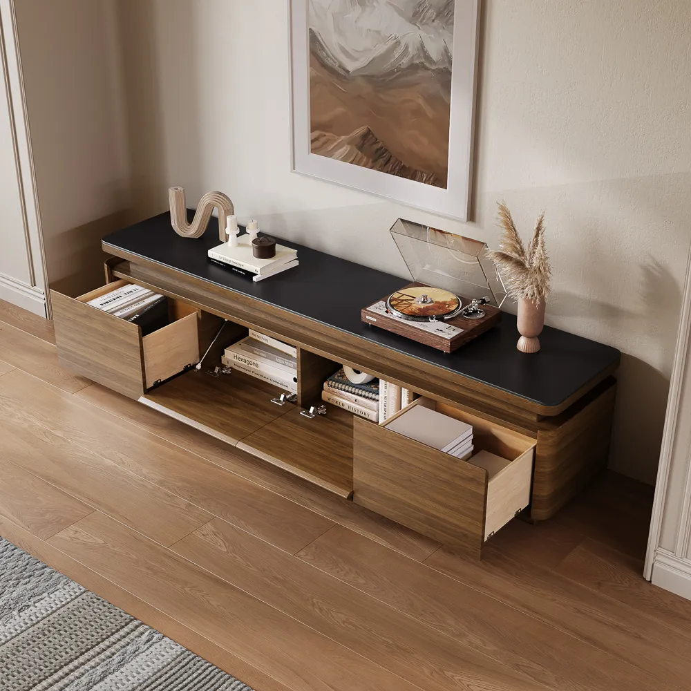 A modern walnut TV console with black top and multiple storage drawers open, displaying books and accessories in a clean living room setup.
