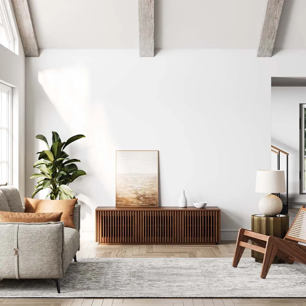 Bright living room featuring a modern walnut slatted TV cabinet, paired with a grey sofa, wood armchair, and neutral area rug under vaulted ceiling