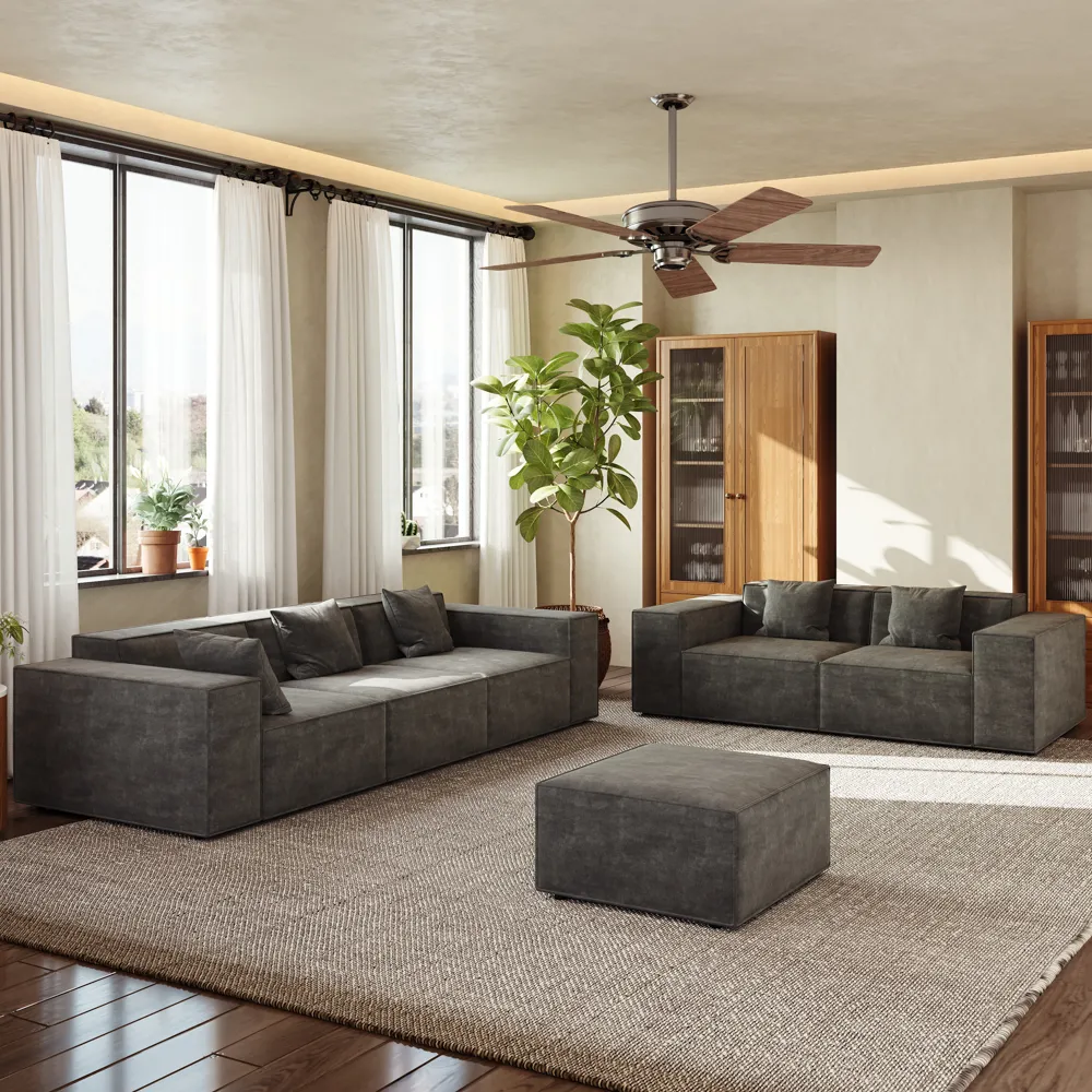 Spacious living room with matching dark gray boxy sofas, ottoman, and wooden cabinets, styled in a neutral palette with natural light and potted greenery