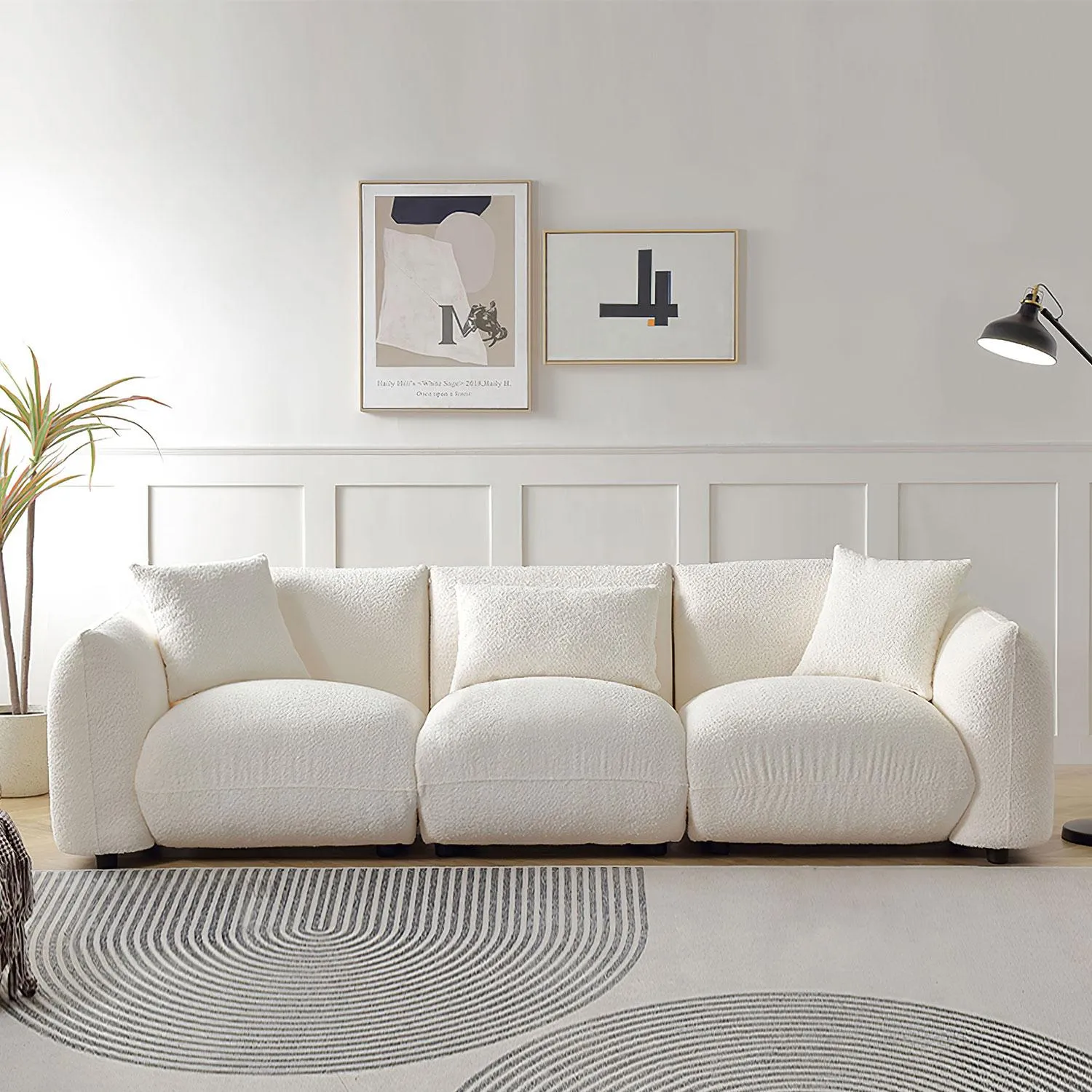 White fluffy 3-4 seater sofa with rounded edges and soft texture, styled in a minimalist room with modern art and curved rug patterns.