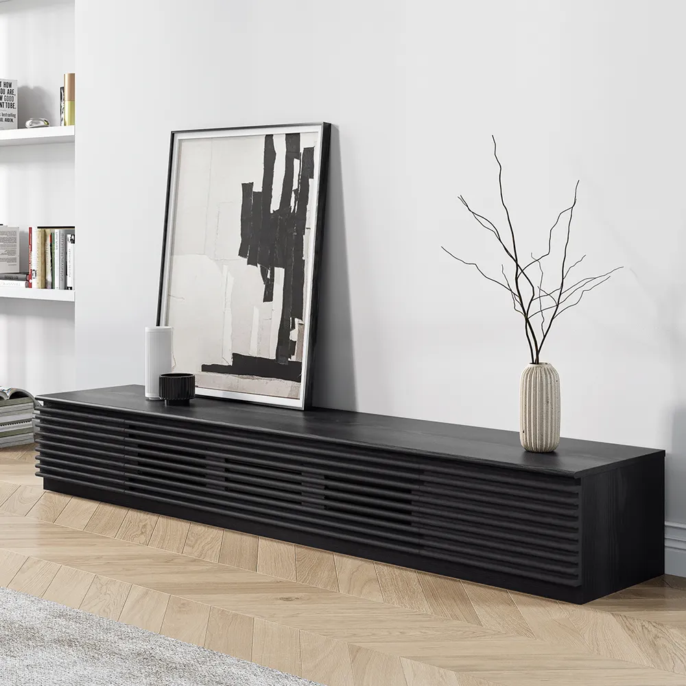 Low-profile black fluted TV stand with artistic decor and abstract wall art in a minimalist living room setup