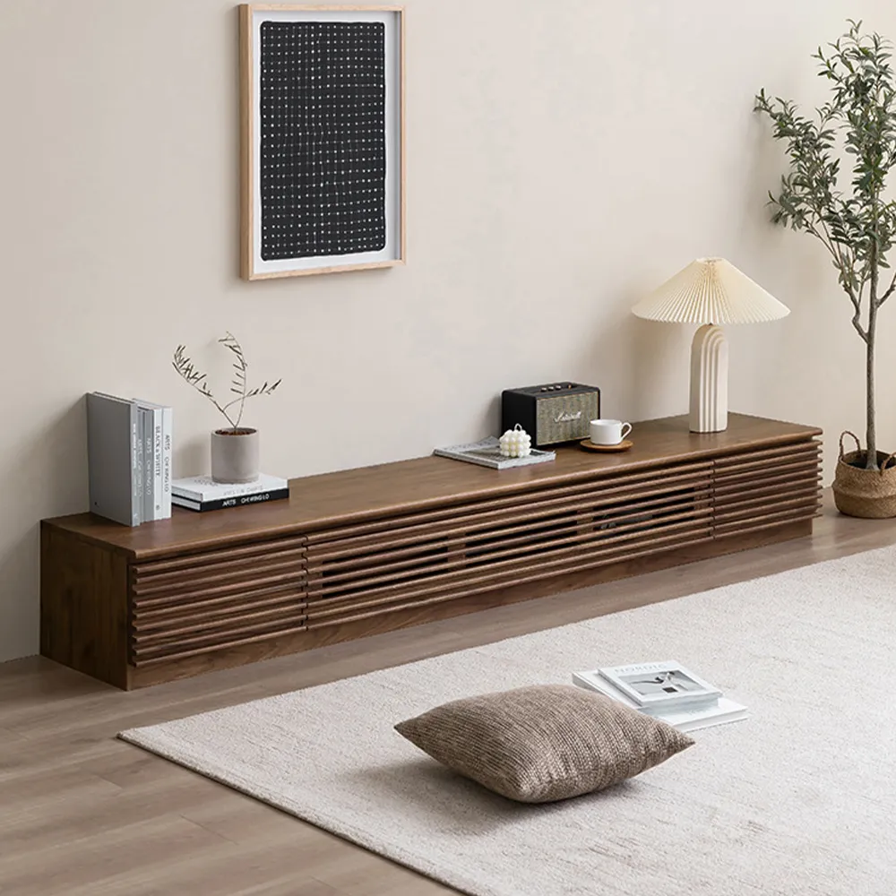Minimalist slatted wood TV stand in walnut finish, styled with a pleated lamp, potted olive plant, and framed graphic art in a Japandi-inspired living space
