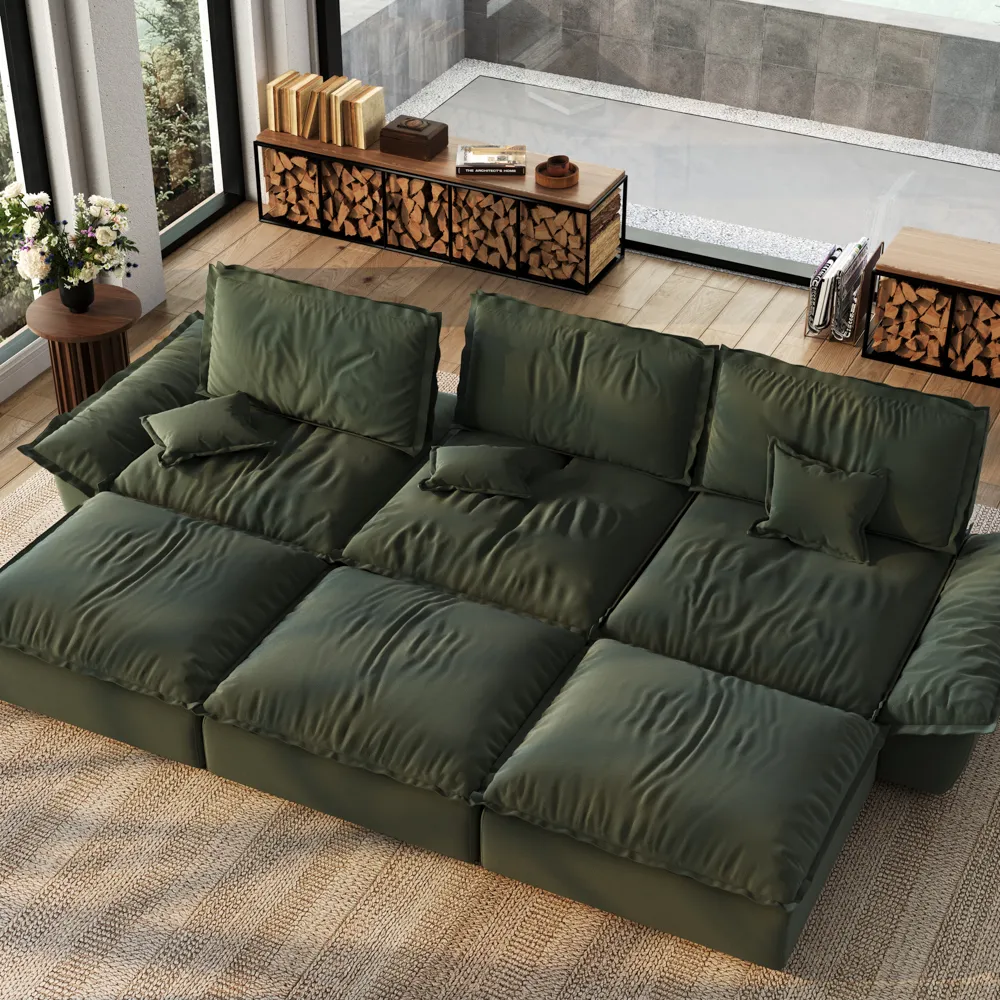 Oversized deep green modular sleeper sofa with three ottomans, styled in a modern sunlit living room with wood accents and glass walls.