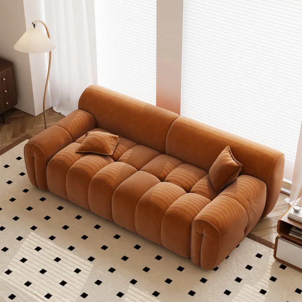 Caramel-colored hand-tufted deep sofa with sculptural curves and velvet texture in a sunlit room
