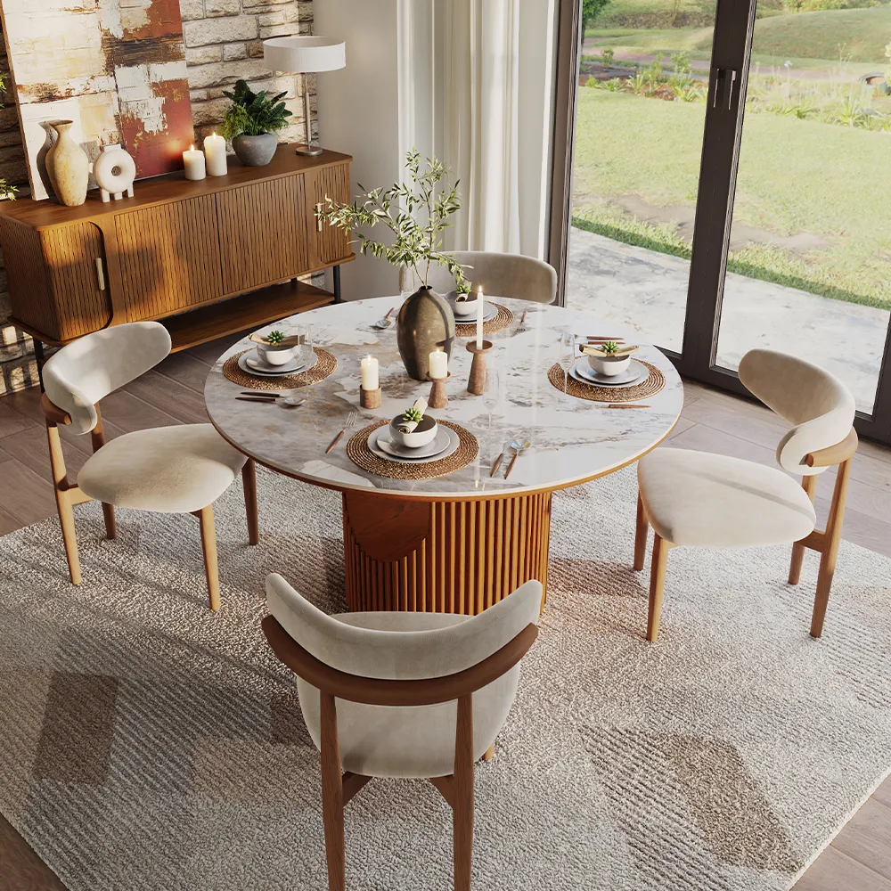 Modern dining space with round sintered stone table and wood base, surrounded by velvet chairs and soft candlelit decor.