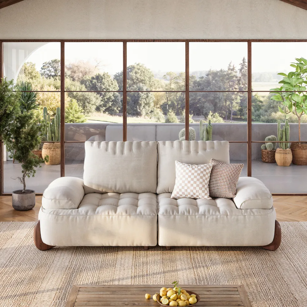Modern tufted beige loveseat with rounded wooden feet and decorative throw pillows, ideal for cozy, sun-filled rooms