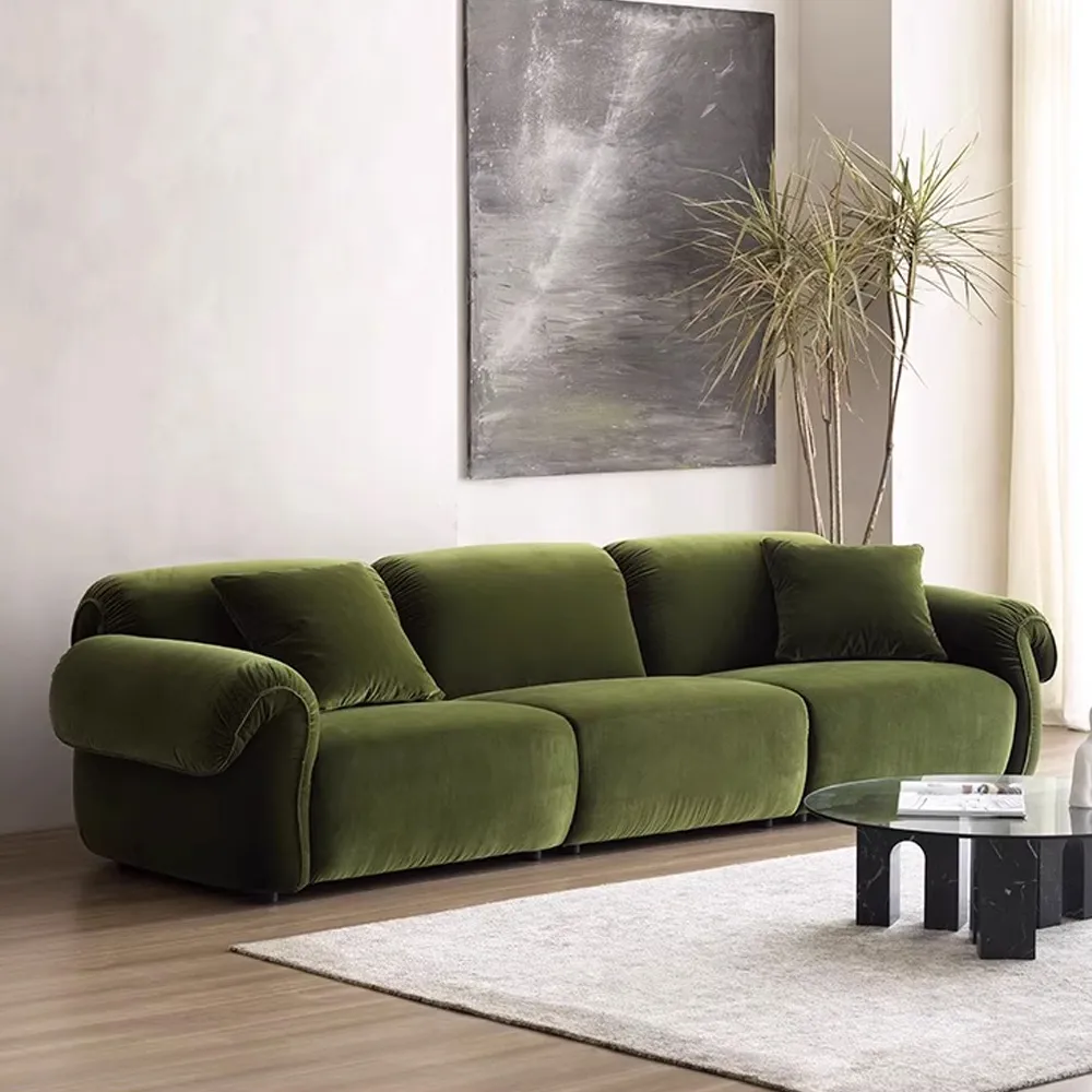 Vintage-style deep green velvet sofa with rounded arms, styled in a modern living room with light wood flooring