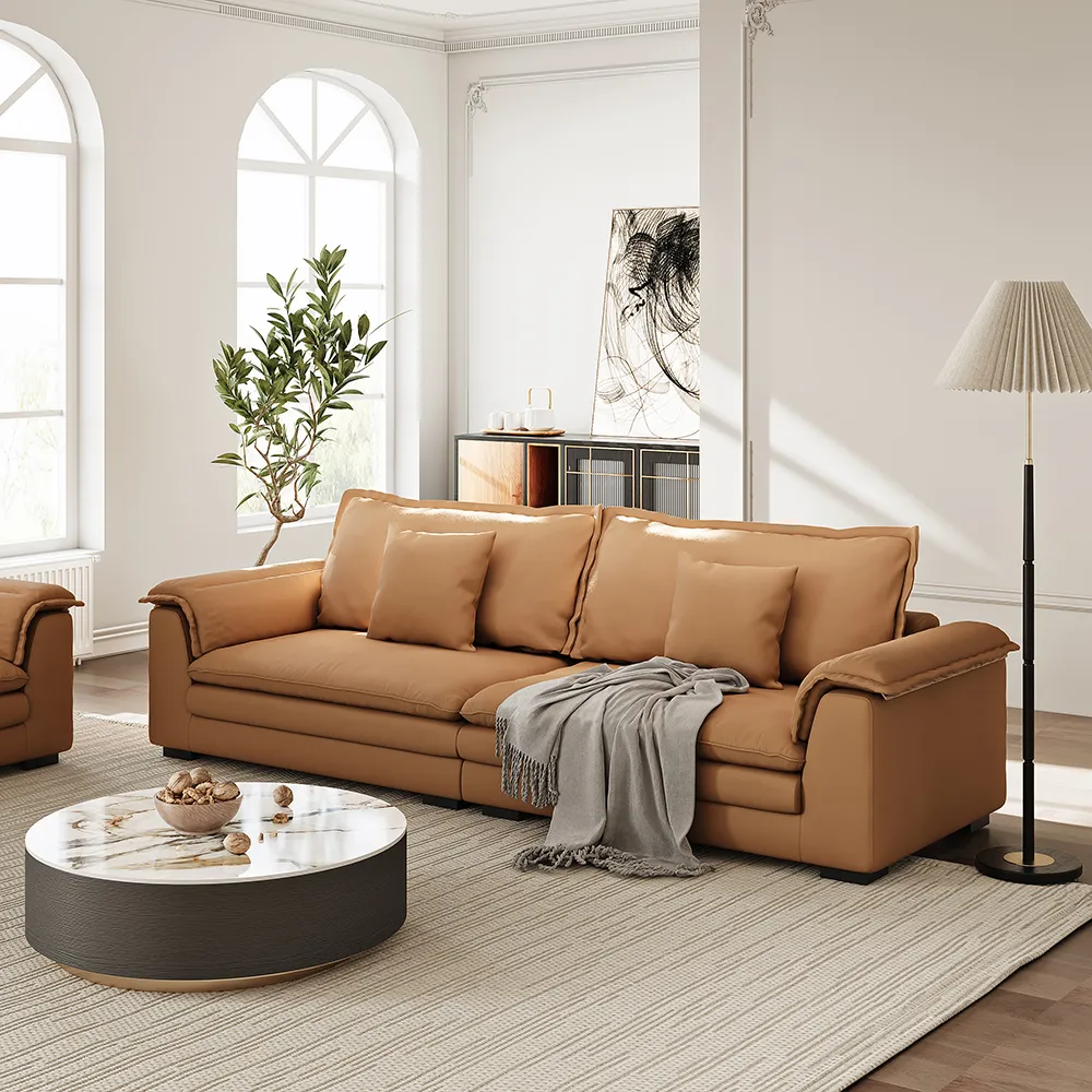 Modern deep seat tan sofa with plush cushions in a white living room, featuring arched windows and a marble coffee table