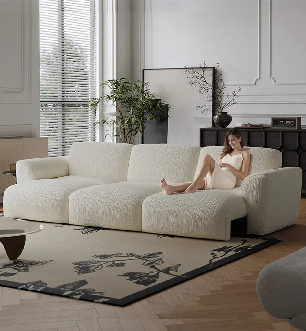 Woman relaxing on oversized French cream power sofa bed in elegant living room with large windows and wood flooring