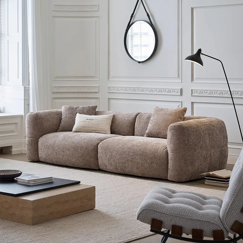 Textured fabric sofa with soft round edges and accent pillows, styled in a classic white-paneled living room with cozy ambiance
