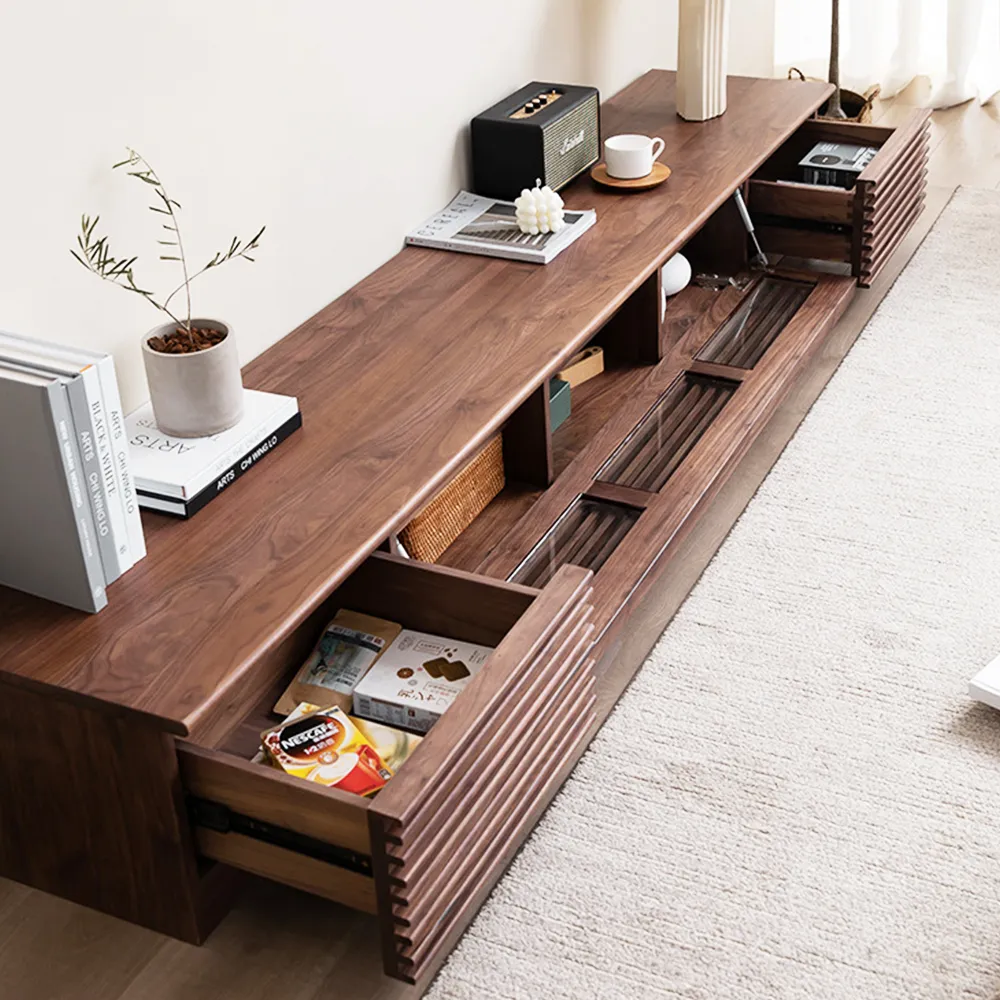 Modern walnut low-profile TV stand with open shelves and sliding drawers, styled in a minimalist living room