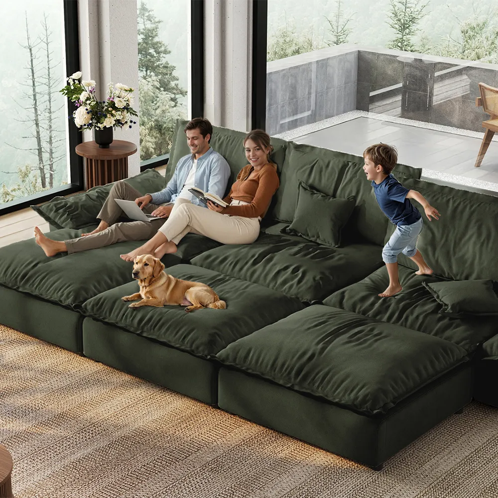 Family lounging on a spacious green modular sofa with a dog and child playing, set in a bright, nature-facing living room with floor-to-ceiling windows.