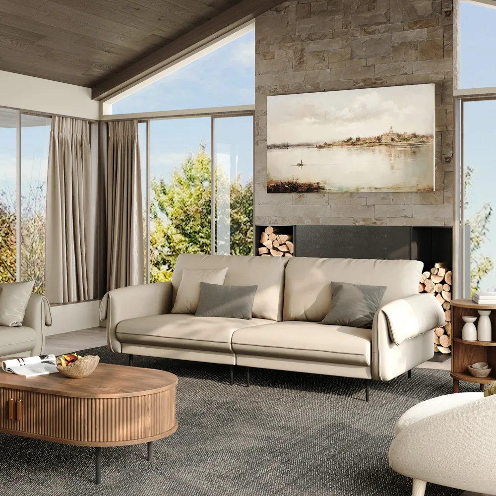 Modern beige sofa with curved armrests styled in a cozy living room with floor-to-ceiling windows and a stone fireplace backdrop