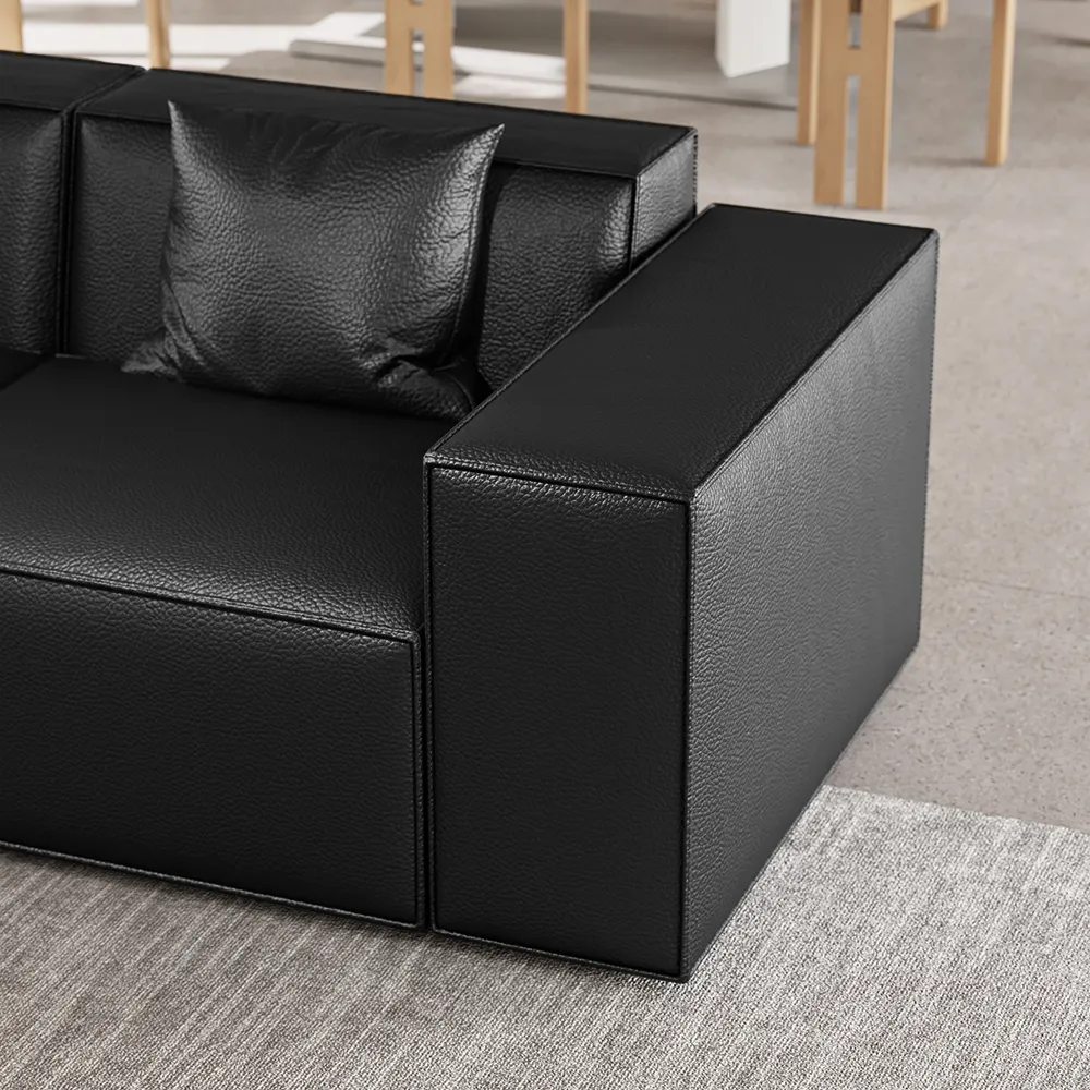 Close-up of modern black leather sofa armrest with textured surface and matching leather cushion on neutral carpet