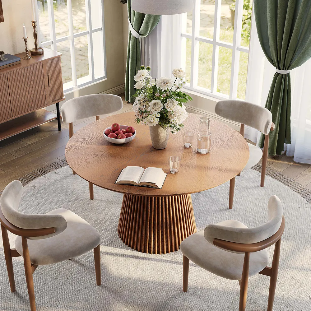Mid-century modern round dining table set for 4 in walnut finish with fluted pedestal base, styled in a sunlit breakfast nook with neutral velvet chairs and fresh floral centerpiece.