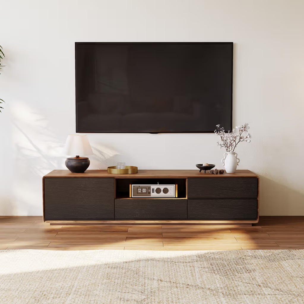 Low-profile wood TV stand with rounded edges, storage drawers, and open media shelf beneath a wall-mounted TV.