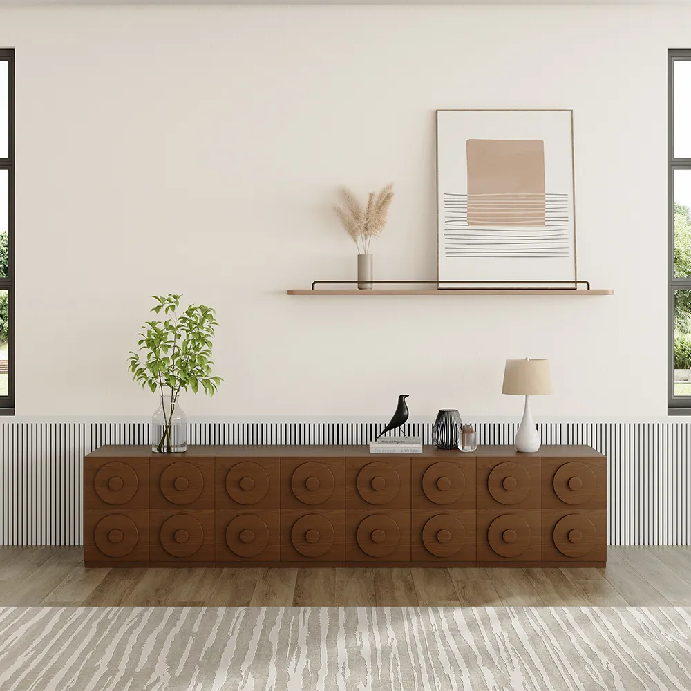 Contemporary modular walnut TV cabinet with geometric carved circles, decorated with modern vases, black sculpture bird, and warm lighting for a graphic statement wall. 