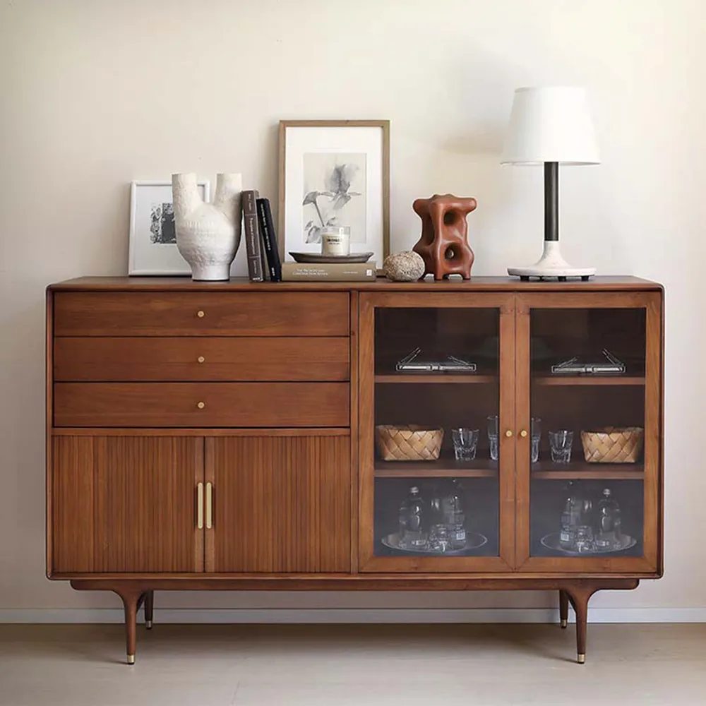 Mid-century modern walnut sideboard with drawers and glass doors, styled with ceramics and books