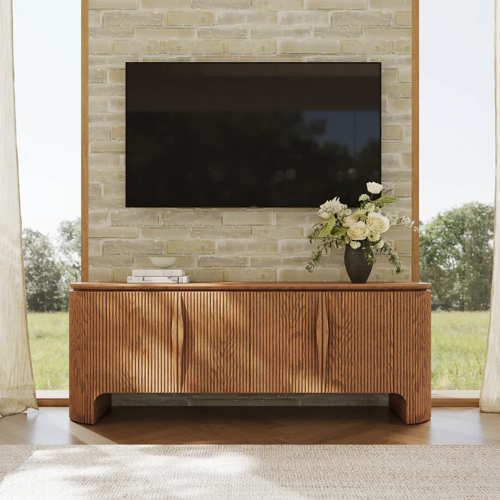 Fluted wood TV console under a wall-mounted screen, styled with floral decor in a bright living space