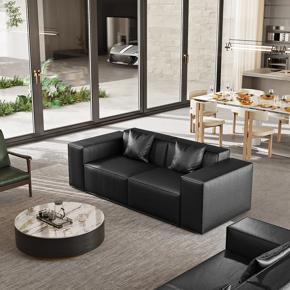 The sleek 83.86-inch minimalist black genuine leather sofa shown in a bright, contemporary open-concept living space.