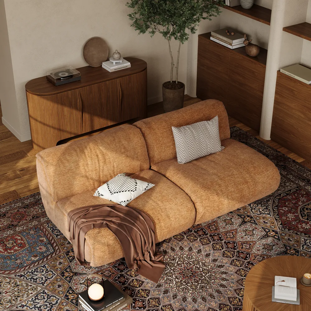 Burnt orange armless modular sofa with textured upholstery, styled with geometric pillows and a throw, set atop a traditional Persian-style rug.