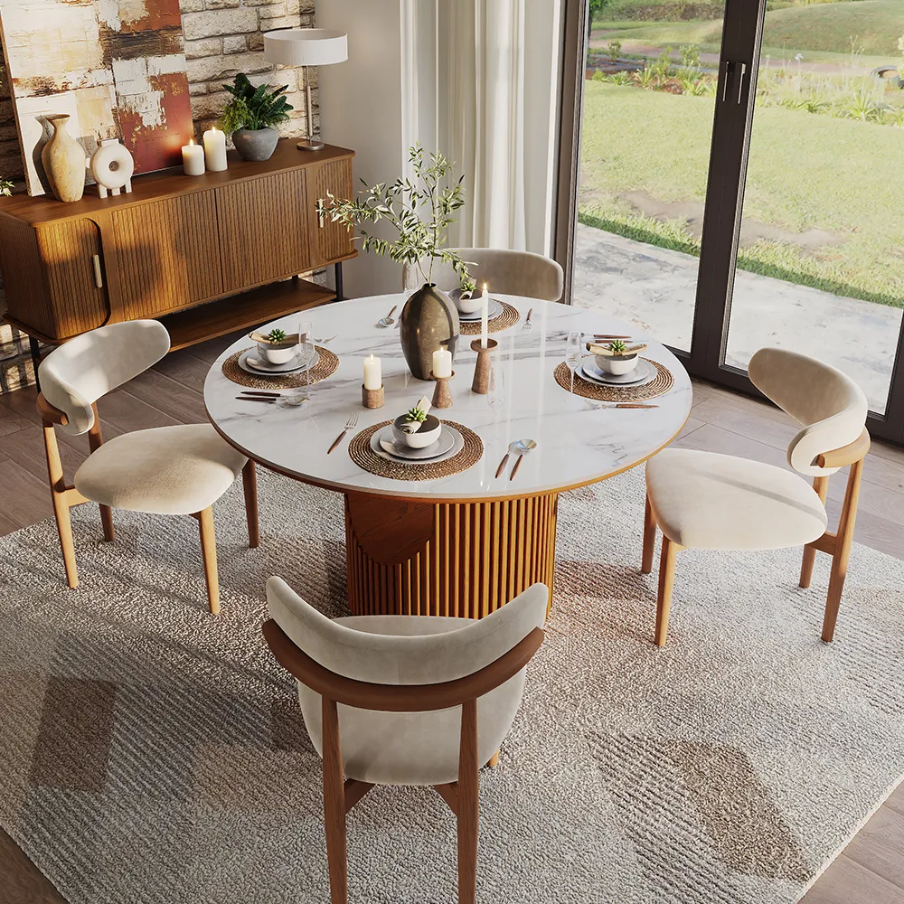 Mid-century modern round dining table with white sintered stone top and fluted walnut pedestal base, surrounded by curved wood dining chairs in a natural light-filled space.
