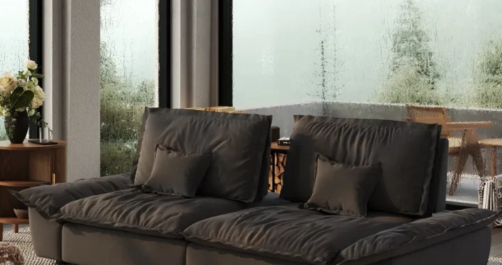 Dark gray mid-century modern sofa with plush cushions and clean lines, styled in a minimalist living room with large glass windows and wood accents.