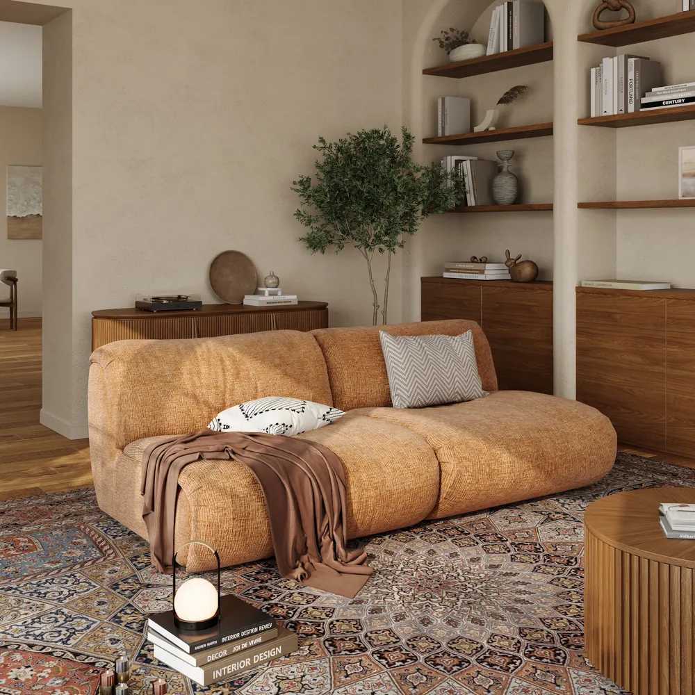 Rust-colored mid-century modern sofa in a warm-toned living room with open shelving, wood accents, and a patterned Persian-style rug.