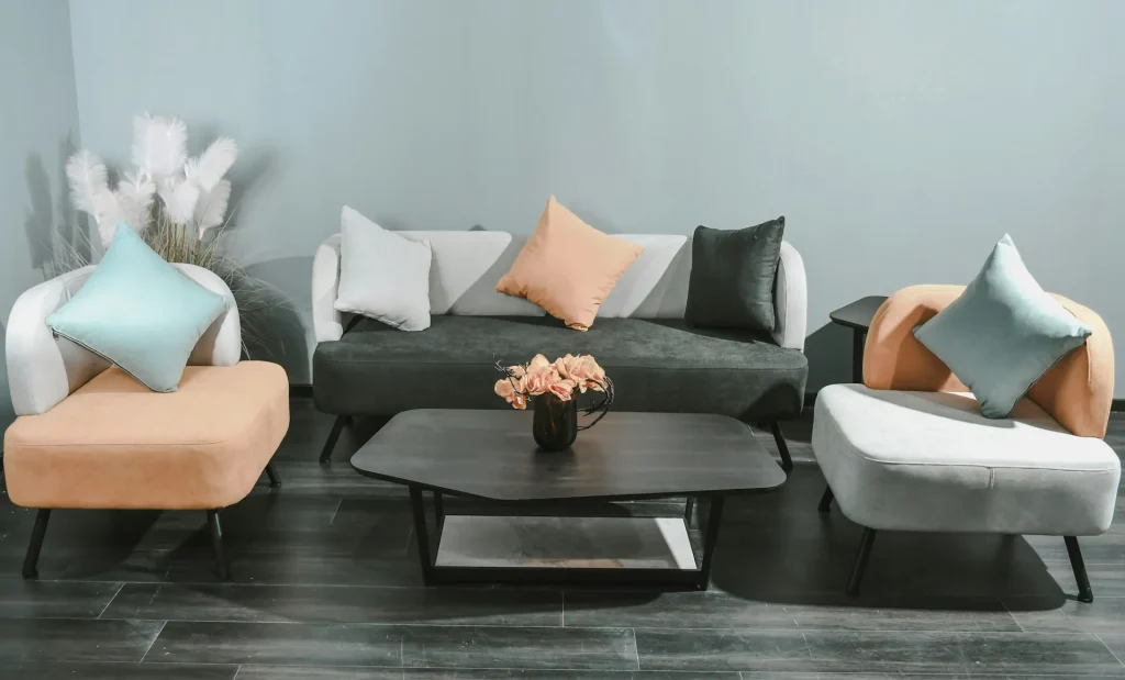 Grey Sofa Living Room Ideas Featuring a Dark Grey Sofa with Peach and Light Grey Accent Chairs and Pastel Cushions in Mint and Coral