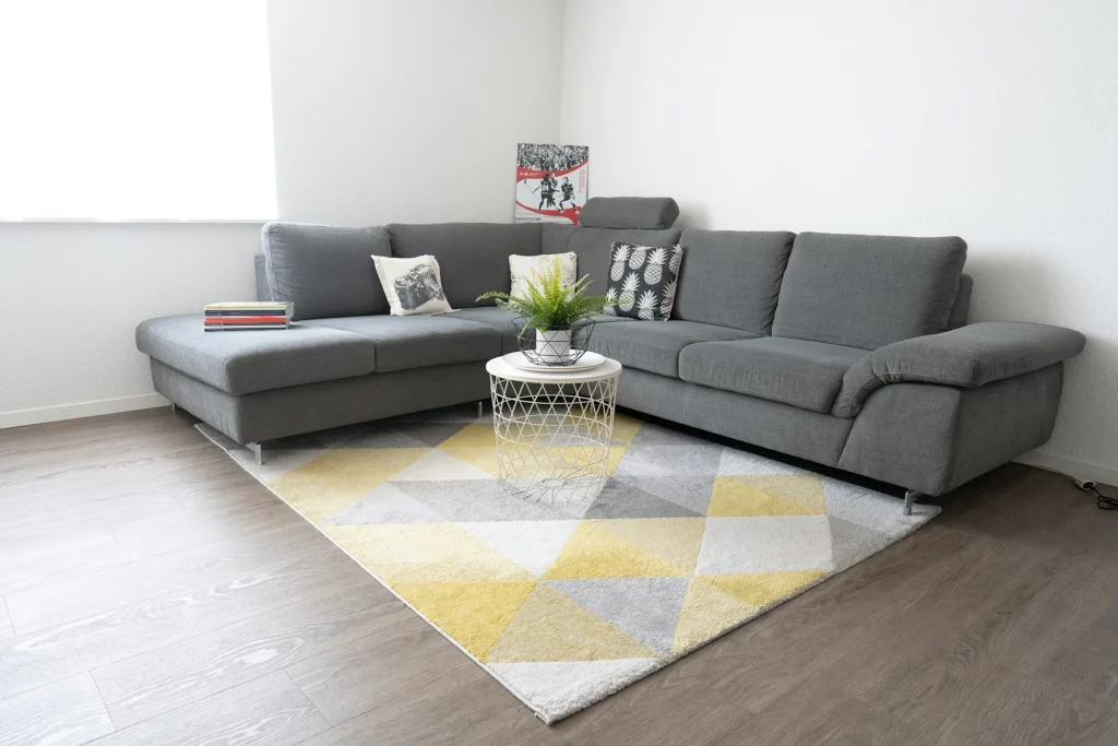 Grey Sofa Living Room Ideas Featuring a Grey Sectional Sofa with a Yellow and Gray Geometric Rug