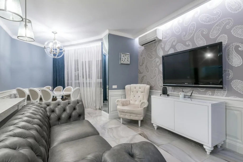 Grey Sofa Living Room Ideas Featuring a Tufted Leather Sofa, Paisley Wallpaper, and a Cozy Cream Armchair