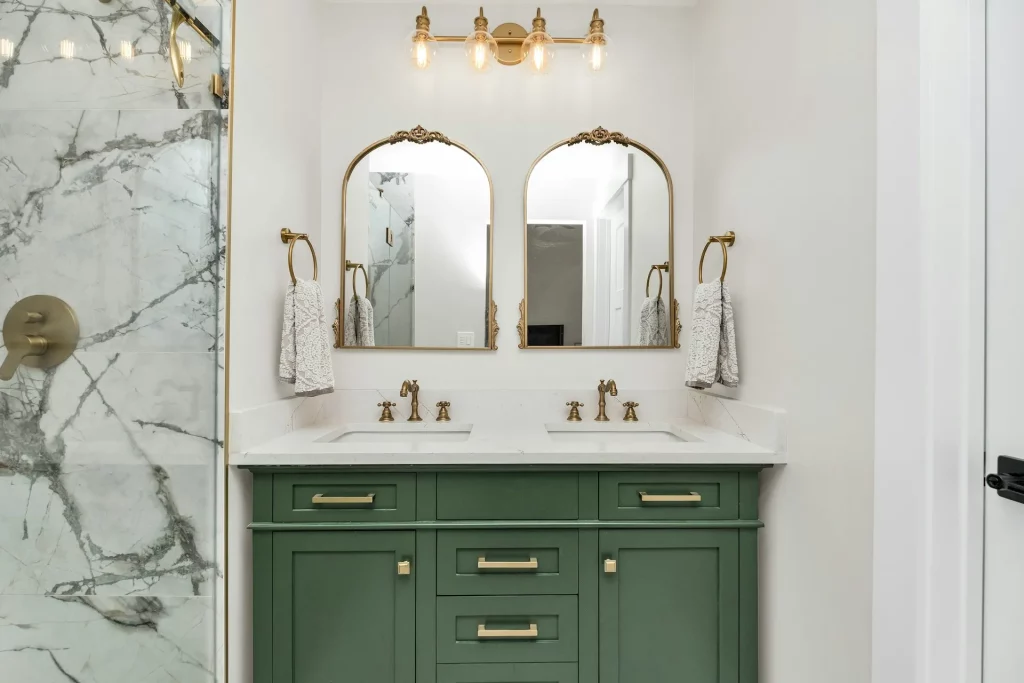 Mid Century Modern Bathroom Ideas Featuring a Green Cabinet, Gold Mirrors, and Marble Wall Tiles