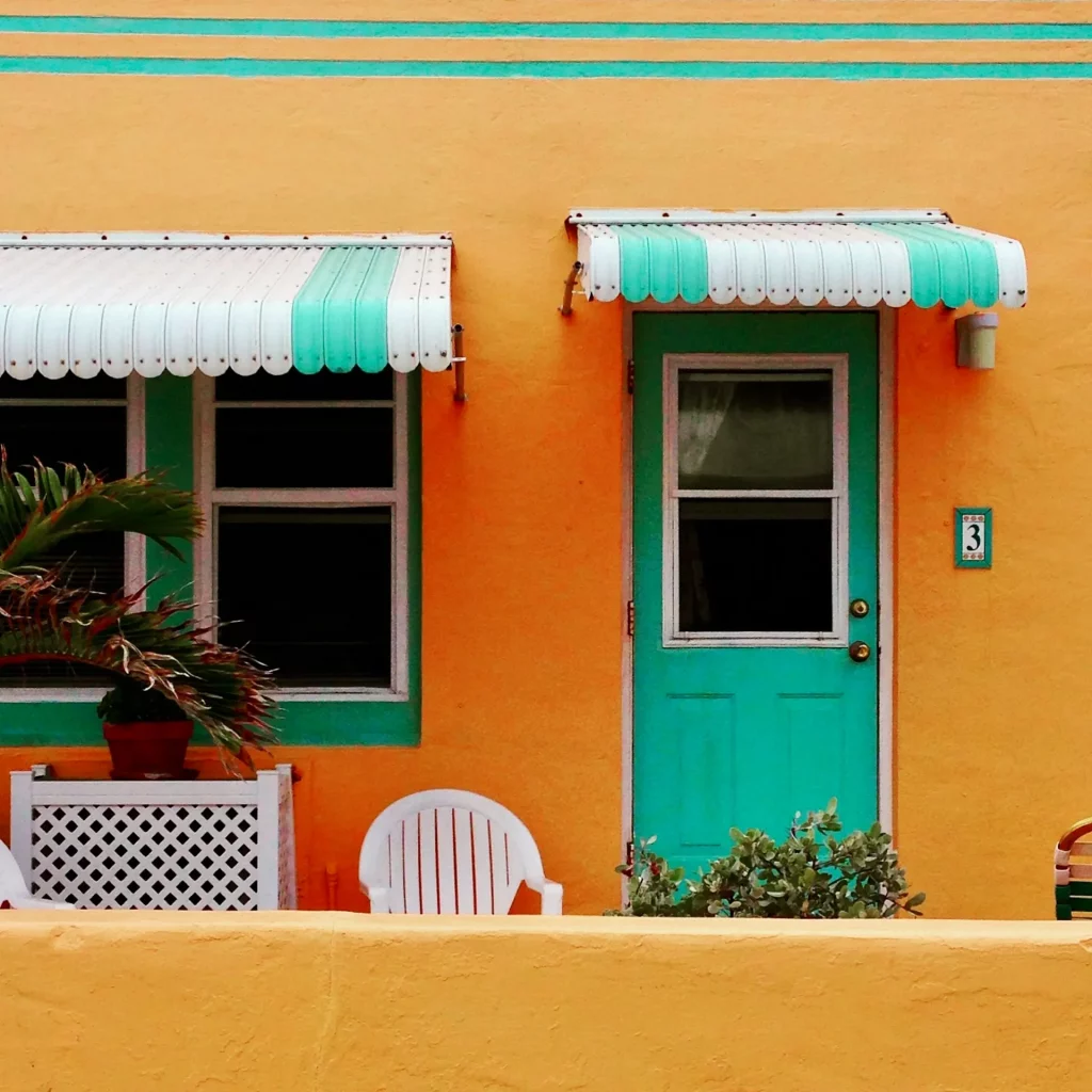 Mid Century Modern Exterior With Bright Mustard Yellow Walls, Turquoise Front Door, and Matching Teal Window Frames