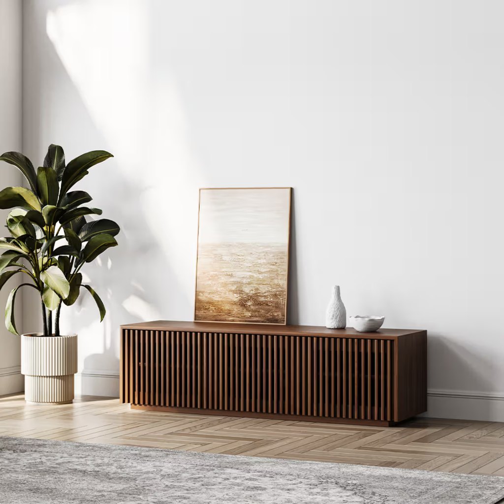 Walnut slatted TV stand with closed storage in a bright minimalist living room.